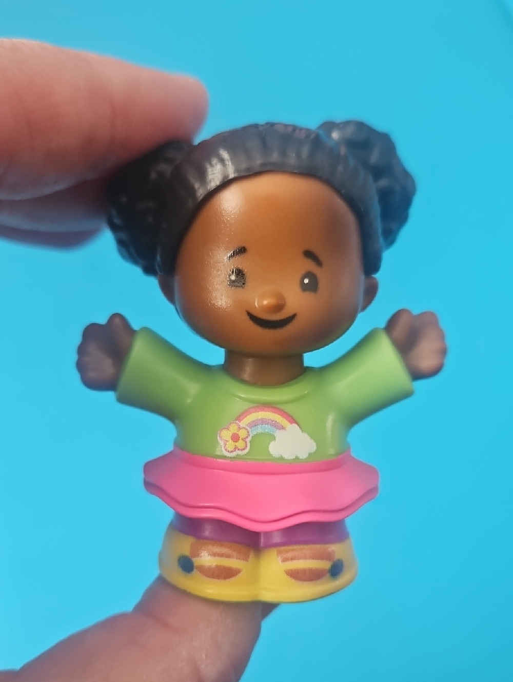 Fisher-Price Little People Tessa figure wearing a rainbow top and pink skirt